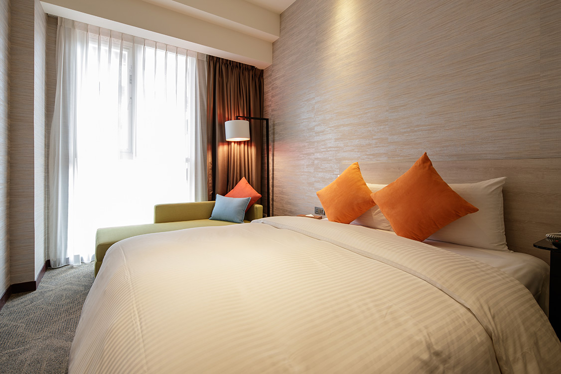 One double bed beside a window in the Deluxe Double Room at VIA Hotel Taipei Station